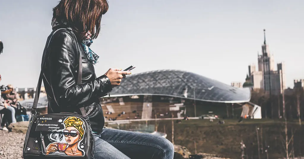 Arnaque aux sentiments: une femme regarde son téléphone en ville