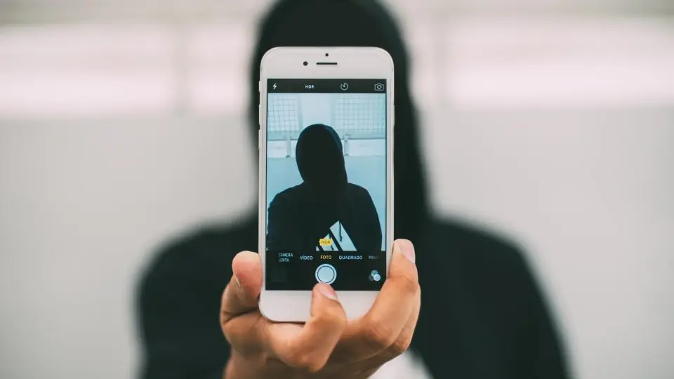 Rencontres en ligne: un smartphone en mode photo tenu devant une personne à capuche