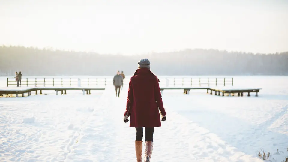 Rencontrer quelqu’un après une séparation: une femme marche seule sur un ponton enneigé au bord d’un lac